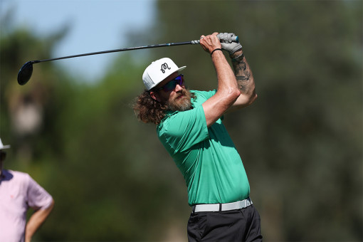 Rhett McLaughlin in a green shirt and white hat playing golf