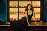 Emmy Rossum in a black gown posing on top of a bar in the Emmy Photo Studio