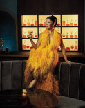 Eunice Bae in a yellow dress with feathers, holding a cocktail in the Emmy Photo Studio