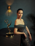 Kate O'Flynn in a strapless gown posing with her Emmy Award