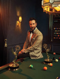 Noah Wyle in tuxedo posing with his two Emmy Awards