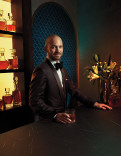 Sean Evans in a tuxedo poses with a cocktail in the Emmy Photo Studio