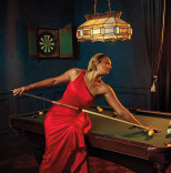 Tiffany Haddish poses on a pool table in a red dress in the Emmy Photo Studio