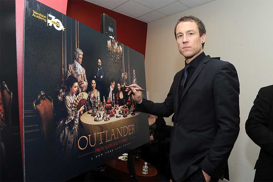 Actor Tobias Menzies signs a poster at the Outlander: From Scotland to Paris event, April 5, 2016, at the NYU Skirball Center for the Performing Arts in New York City. 