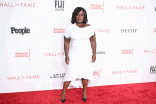 Uzo Aduba wearing a white dress and posing on the red carpet