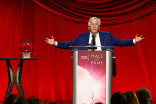 Henry Winkler standing at a podium with his arms out to the side