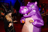 Someone wearing a purple hippo costume holding a drink