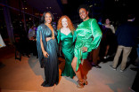 Three women wearing green dresses smiling and posing for a photo outside