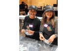 Two women wearing "BIG" branded hats and aprons packing plastic bags