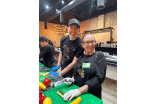 Two participants smiling and posing for a photo while prepping vegetables